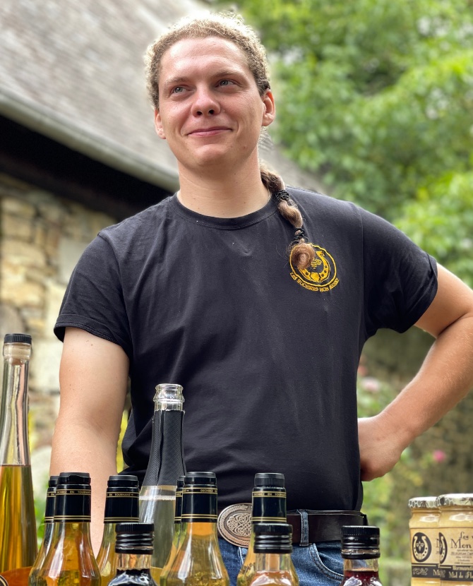 Portrait de Mike Vivien devant ses bouteilles d'hydromel et ses pots de miel